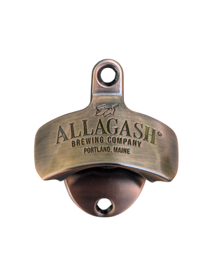 The word "Allagash" depicted inside a white state of maine shape on a red and black checkered koozie