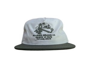 White cap with green brim, green logo featuring a Maine lobster and soccer theme. Green text reading "Allagash Brewing Co. Hearts of Pine Portland, Maine"